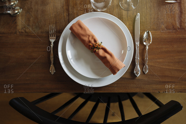 Place setting at a table with orange napkin