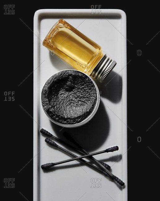 Black beauty scrub and cotton swabs on a white tray