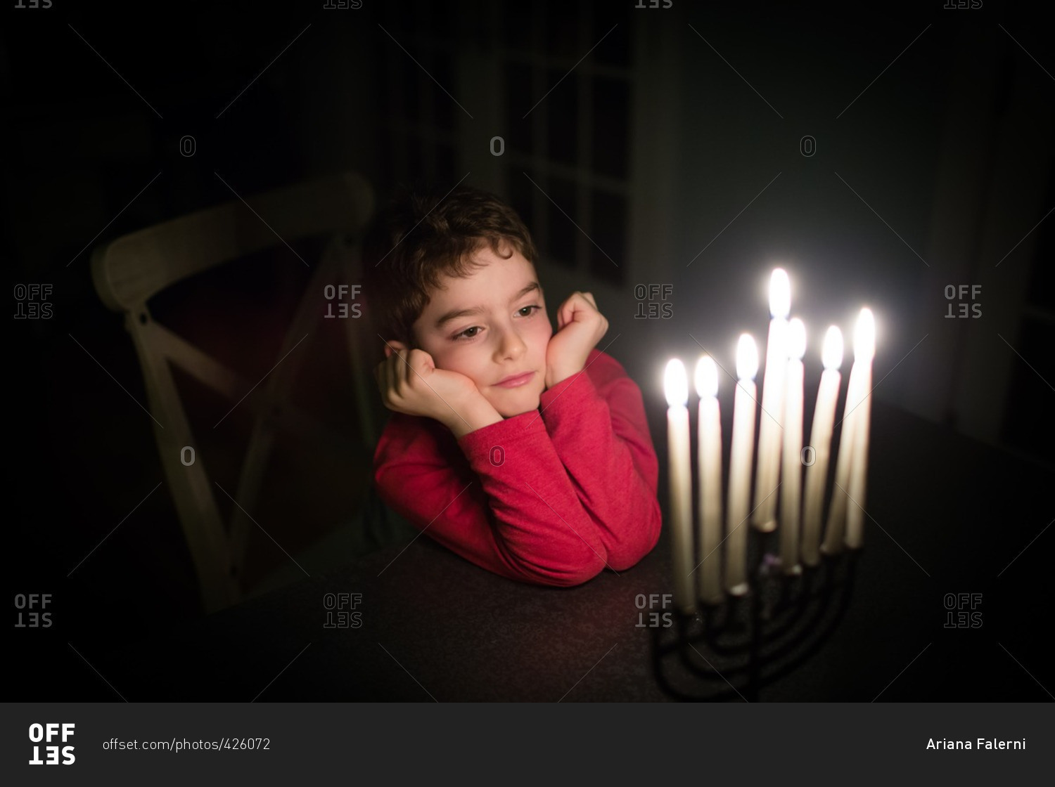 Boy gazing at lit candles on a menorah