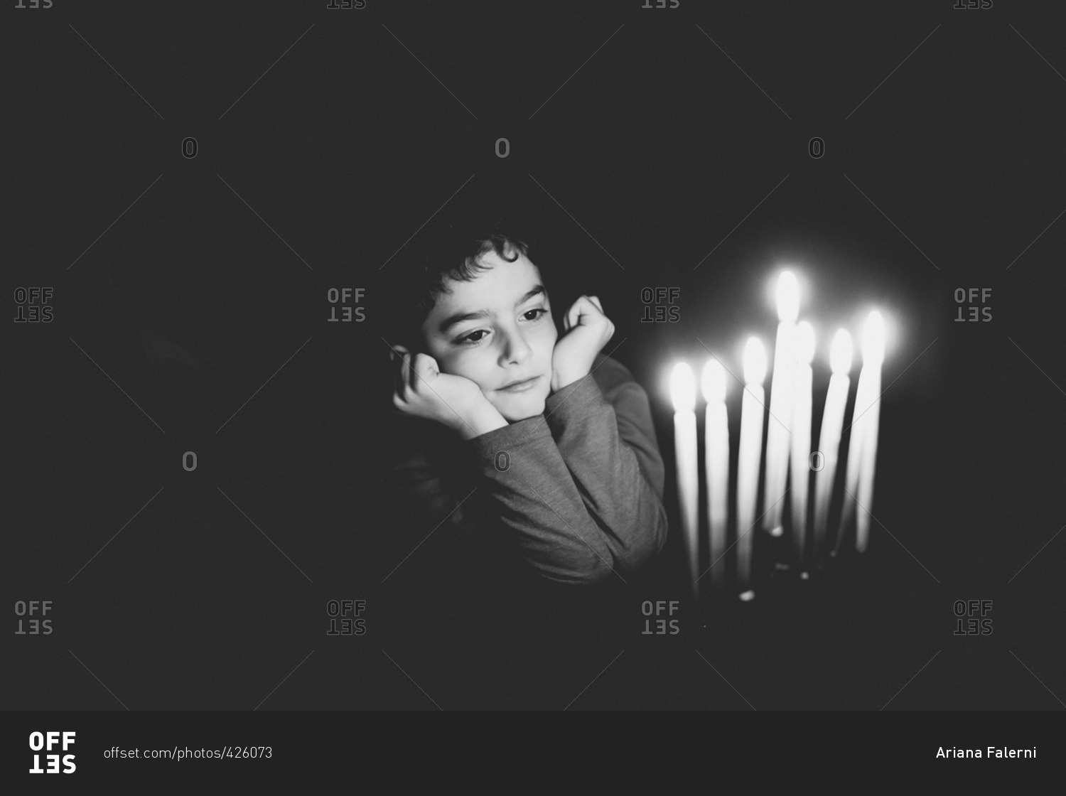 Young boy sitting at table with candles lit in menorah