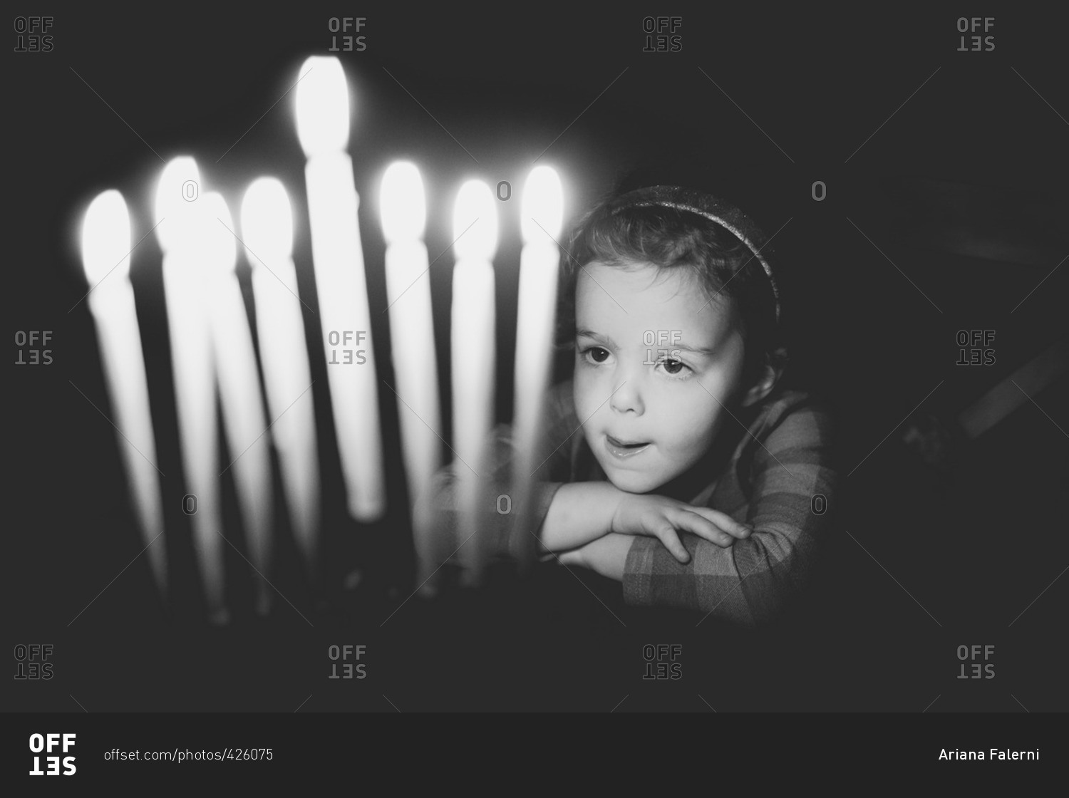 Girl gazing at lit candles on a menorah