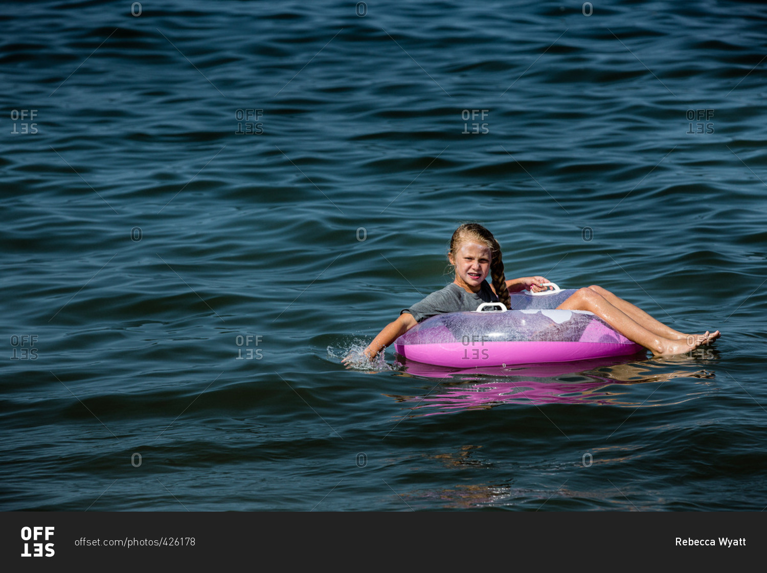 Girl floating on an inner tube in the water stock photo OFFSET