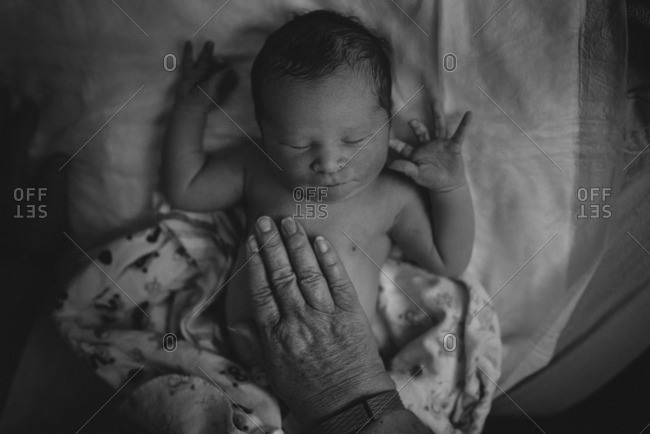 Hand touching newborn's chest - Offset