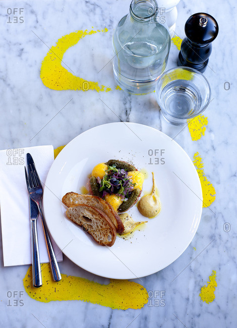 Plate with egg yolks, salad and crostini on a marble surface