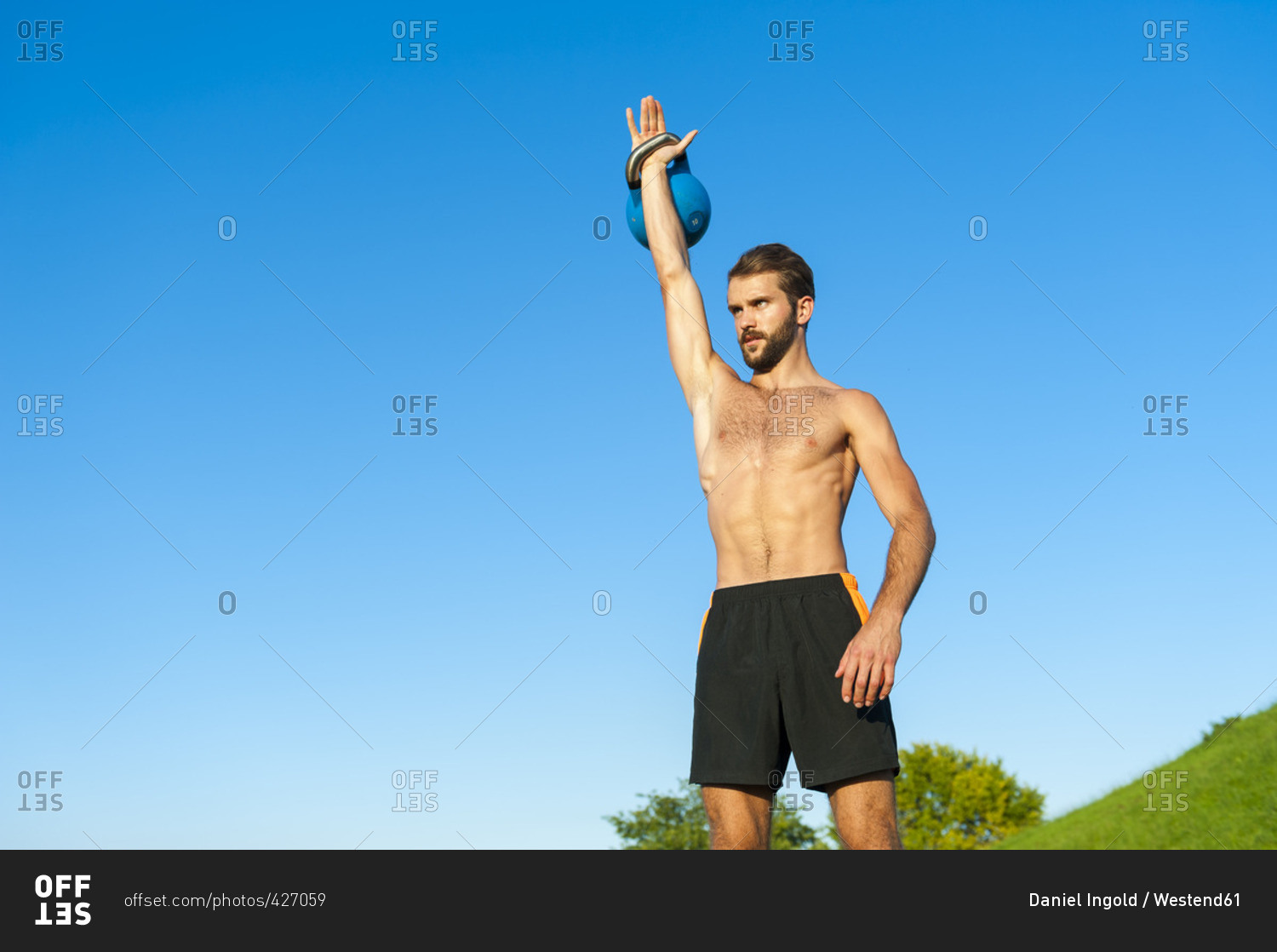 Man exercising with kettlebell under blue sky