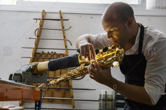 Instrument maker using a scraper during a saxophone repair