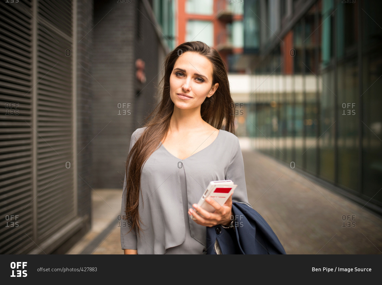 Young businesswoman with smartphone outside office, London, UK