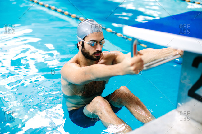 Man in swimming pool holding starting block