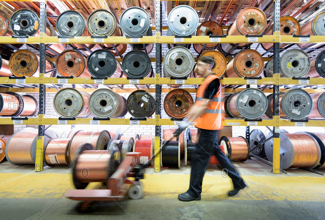 Worker with copper cable reels in cable factory