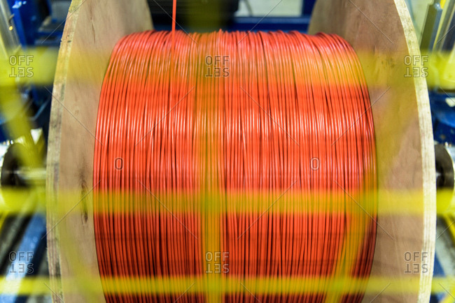 Red cable spinning on spool in cable factory