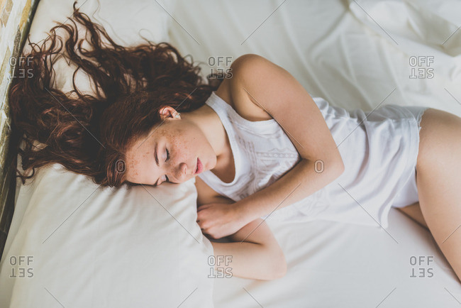Young woman sleeping on soft bed