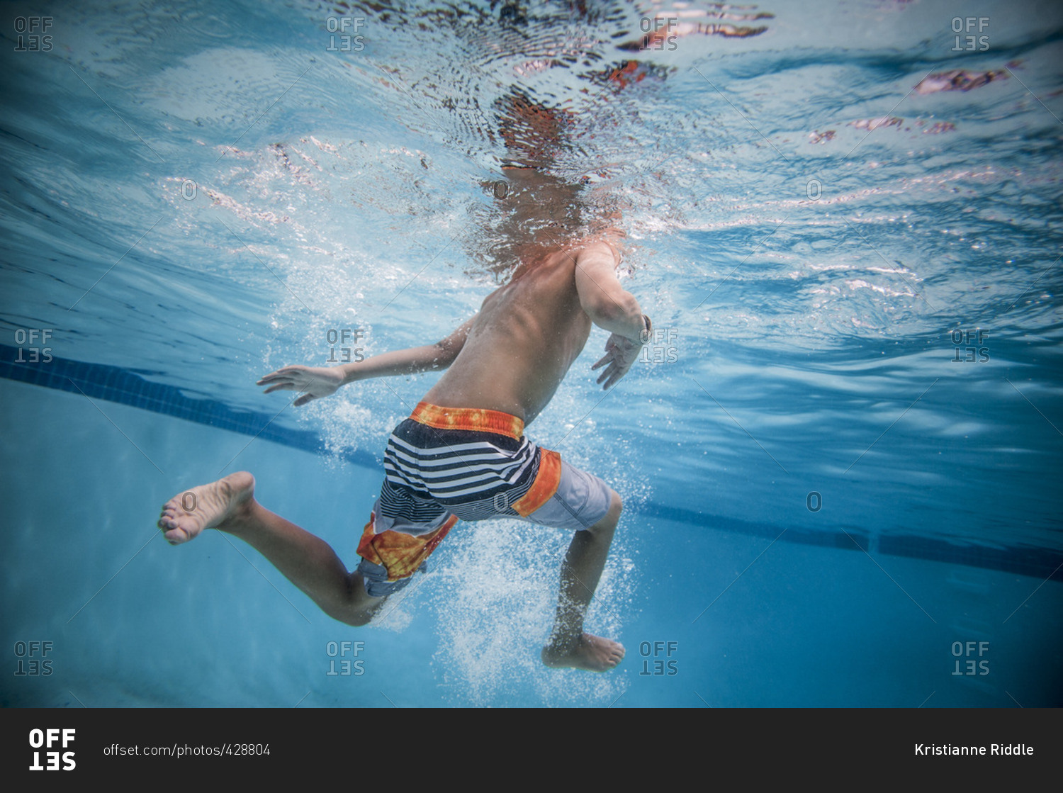 Underwater view of boy kicking feet in a swimming pool stock photo OFFSET