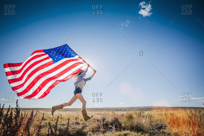 Hispanic woman running in desert carrying American flag