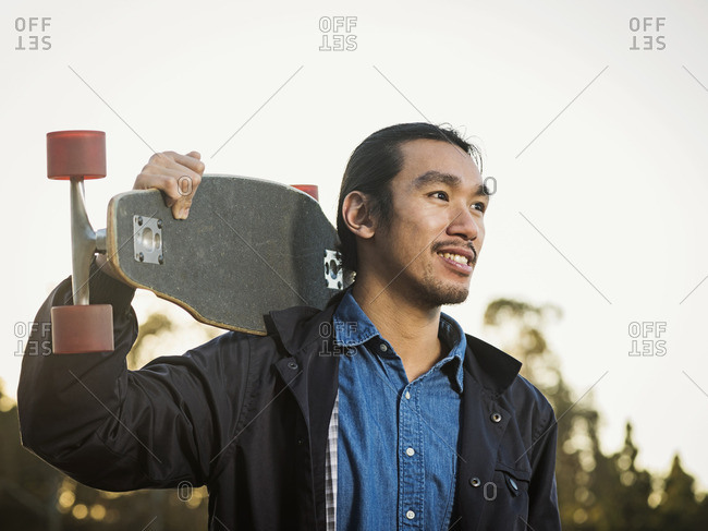 Chinese man carrying skateboard outdoors