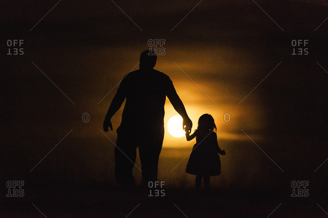 father and daughter holding hands walking