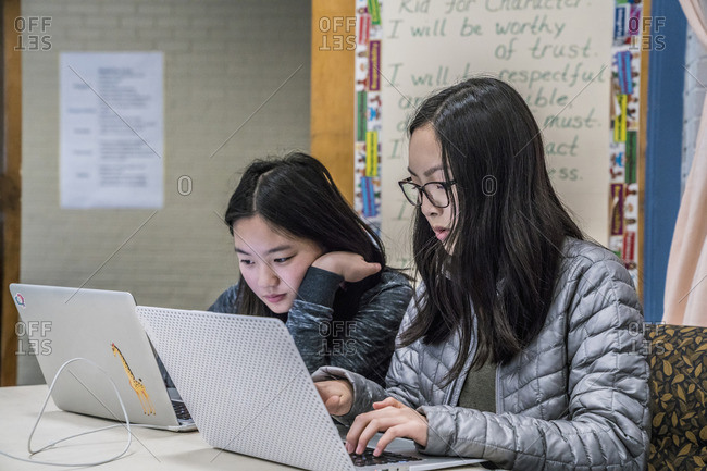 Asian students using laptops at table