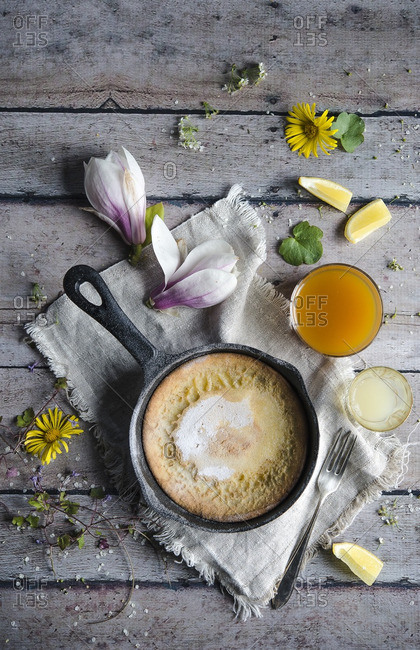 Pancake baked in a skillet arranged with flowers and lemon