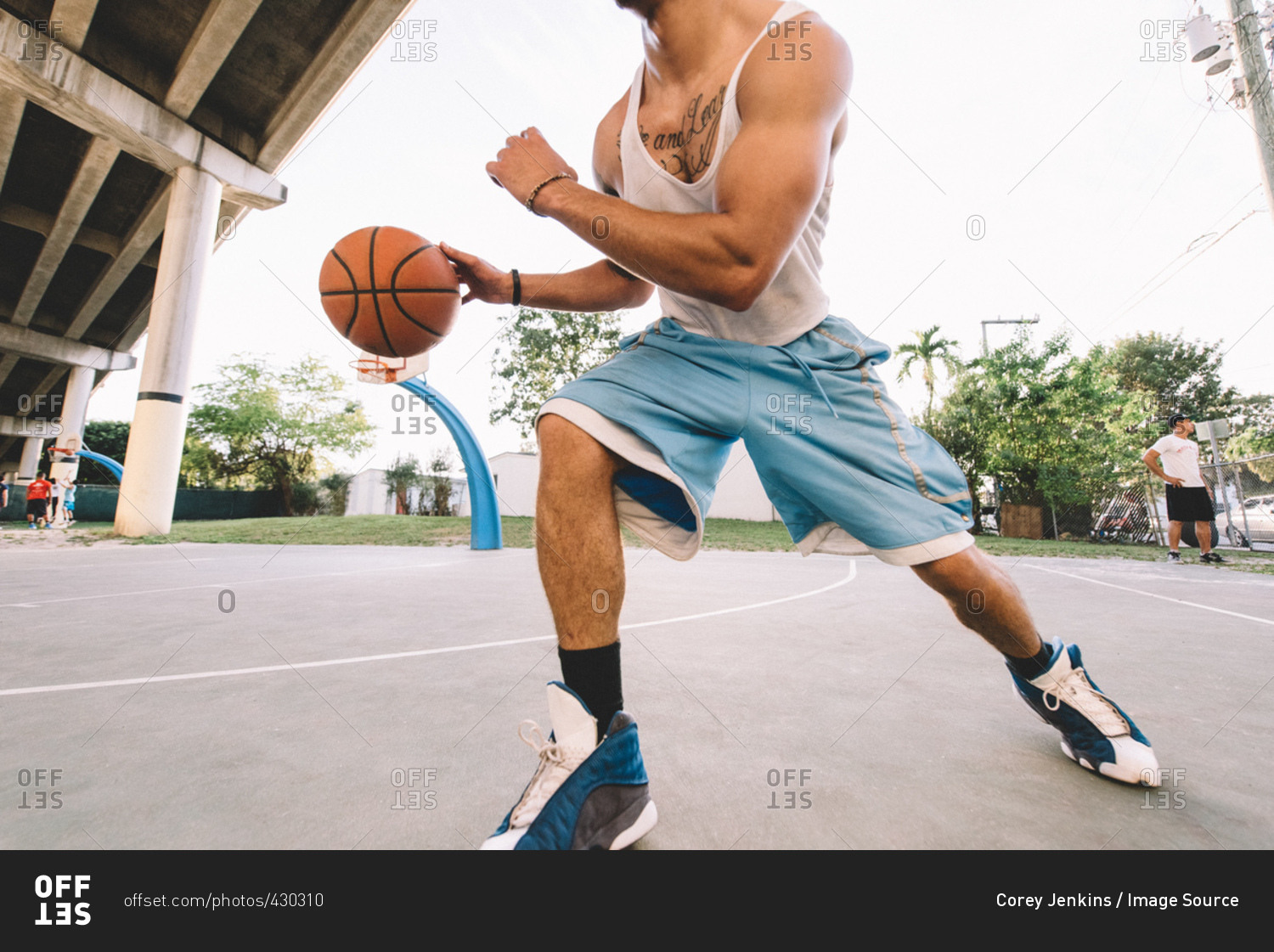 Cropped view of man on basketball court running, bouncing basketball