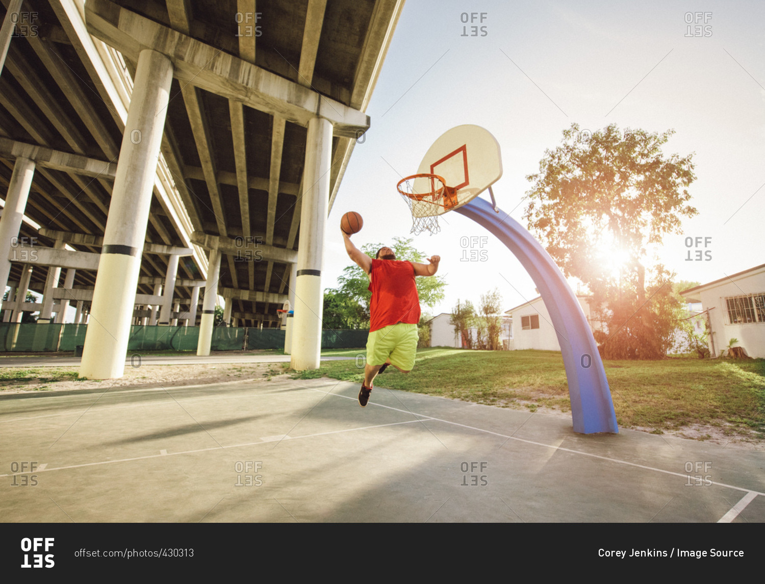 Low angle view of man on basketball court in mid air jumping for basketball hoop