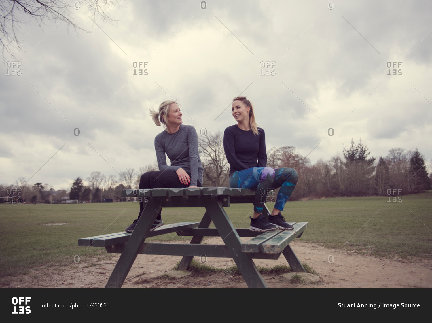 Women wearing sports clothing sitting on picnic table chatting