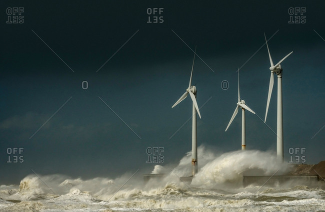 Three wind turbines amidst fierce storm waves and clouds at coast, Boulogne-Sur-Mer, Nord-Pas-de-Calais, France