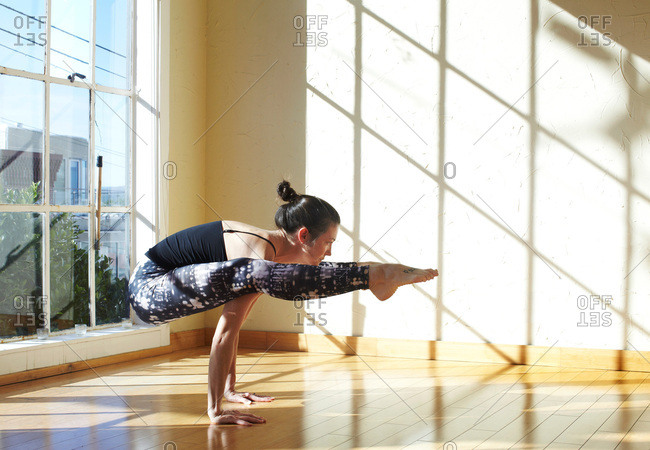 Woman doing yoga in studio, in firefly position