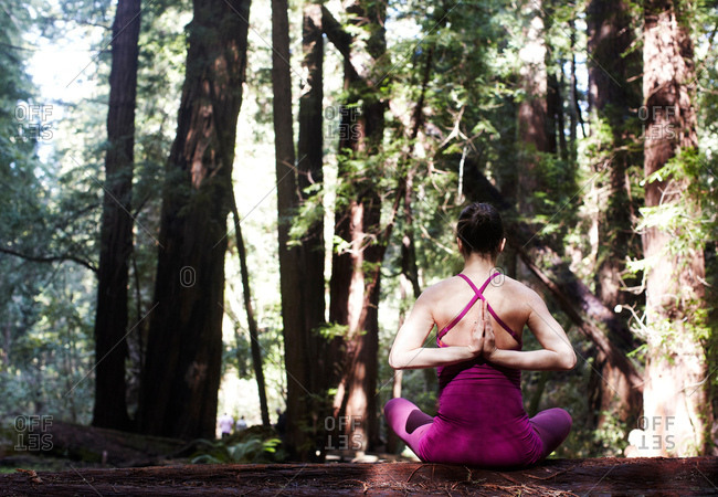 Mid adult woman doing yoga in forest, in prayer pose