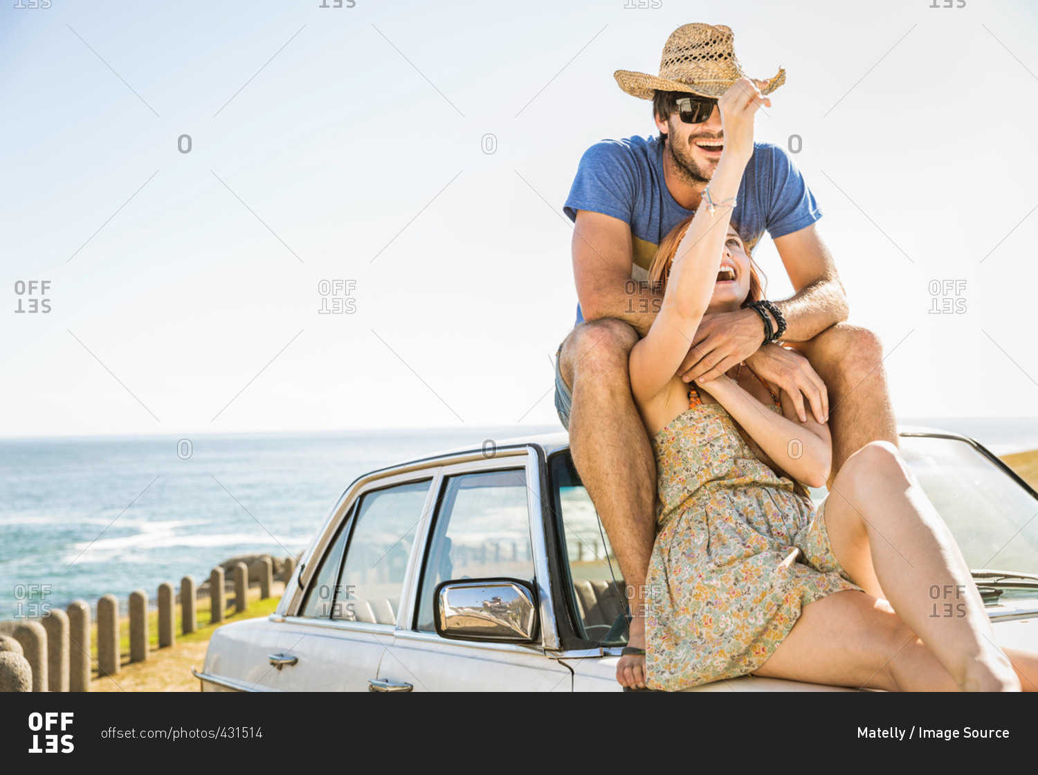 Mid adult couple sitting on top of car on coast road, Cape Town, South Africa