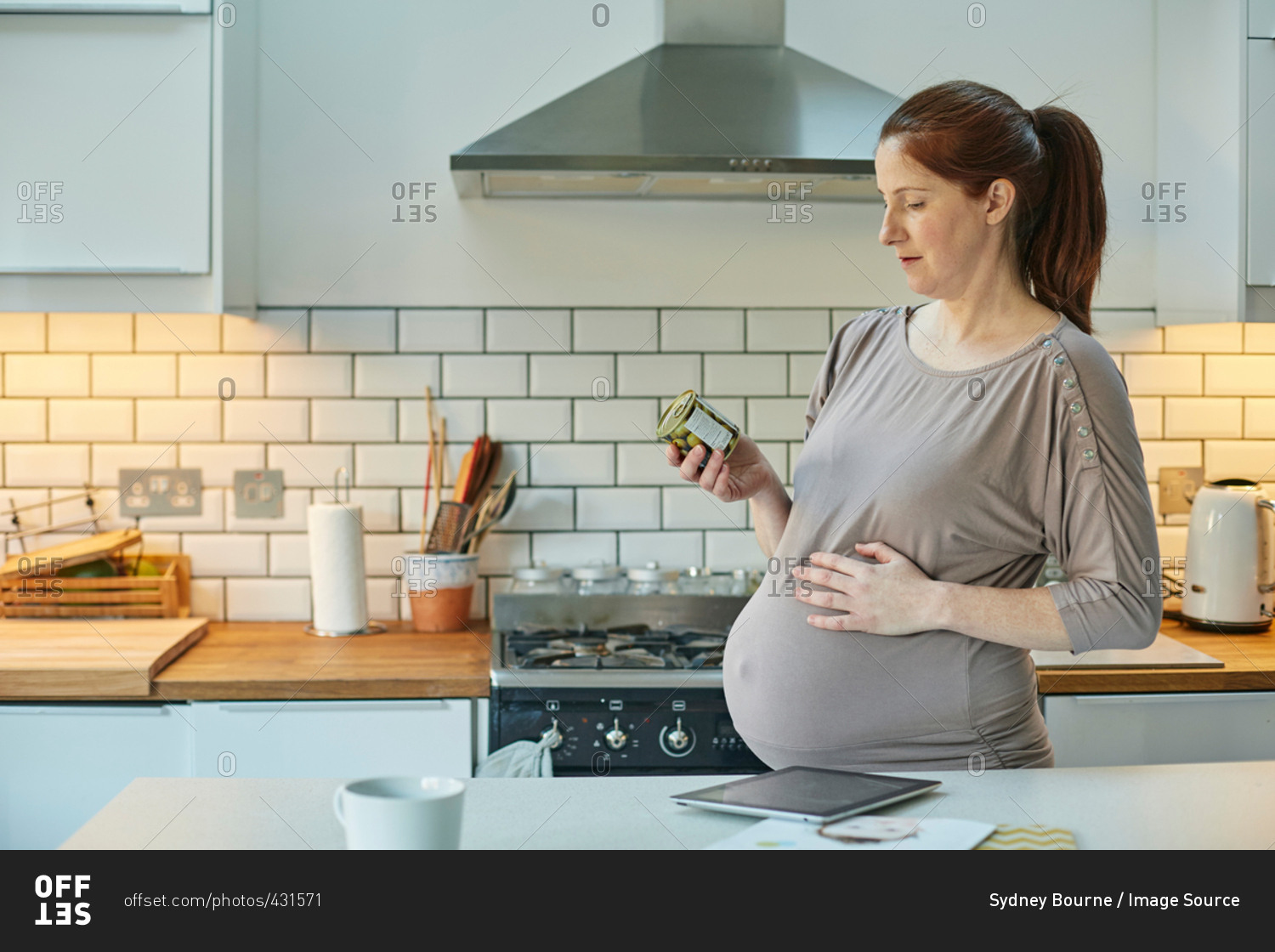 Side view of pregnant woman in kitchen looking at food packaging