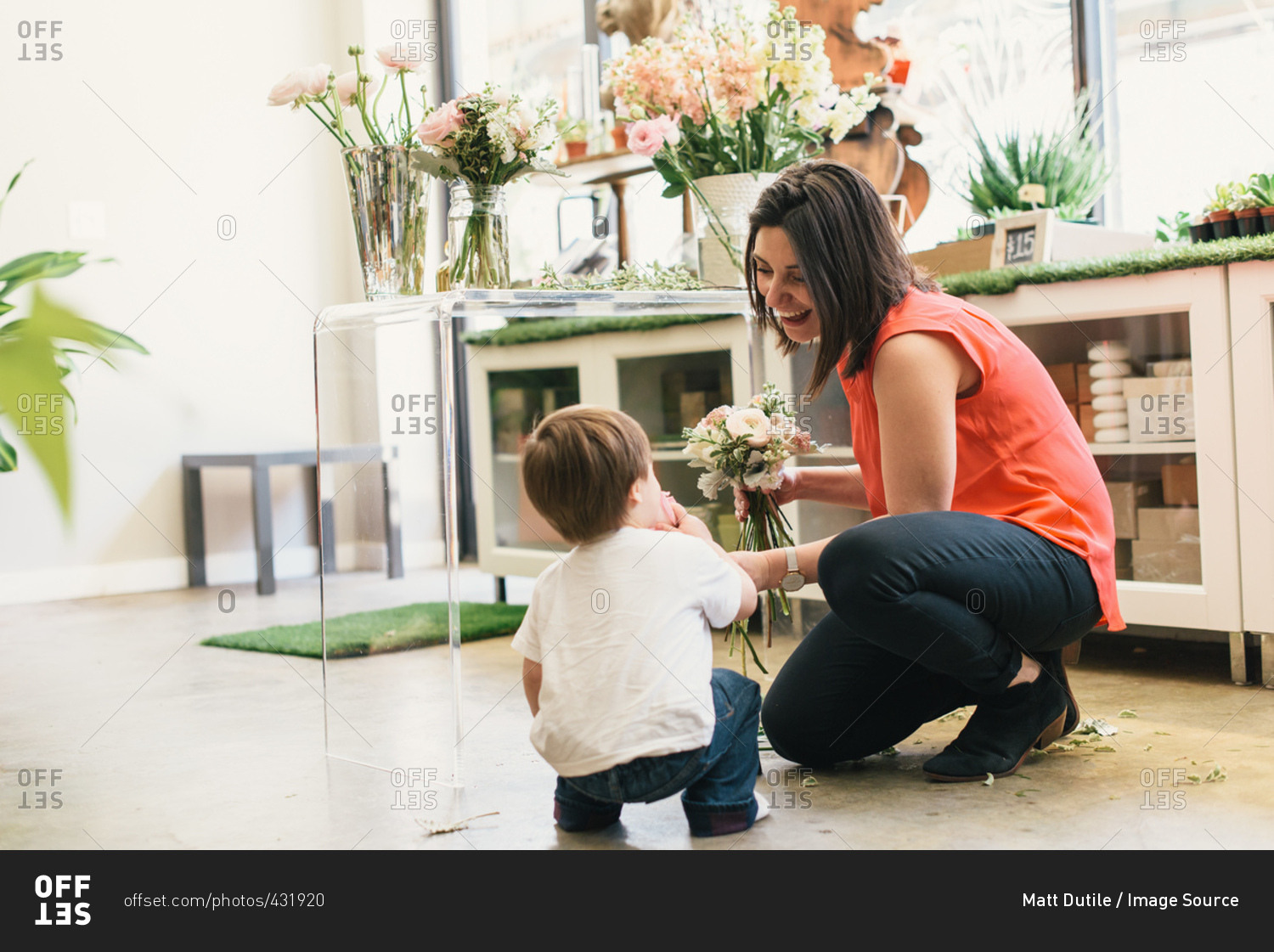 Mother crouching with son in flower shop, mother holding bouquet