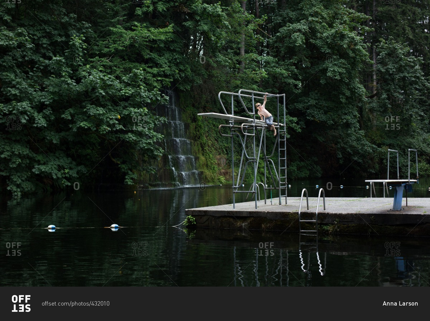 Boy climbing a high dive at a secluded swimming hole
