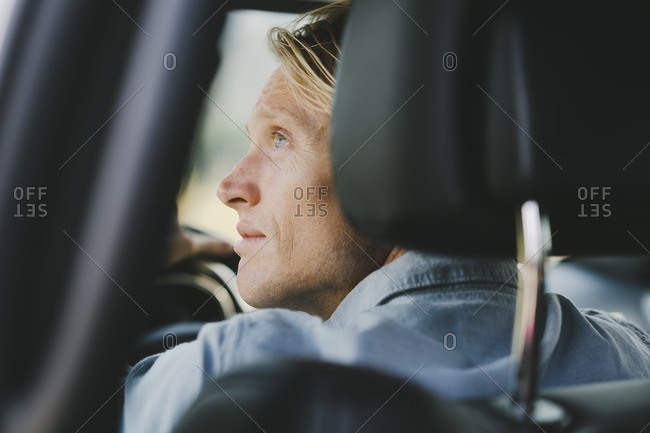 Man in the front seat of a car looking out the window