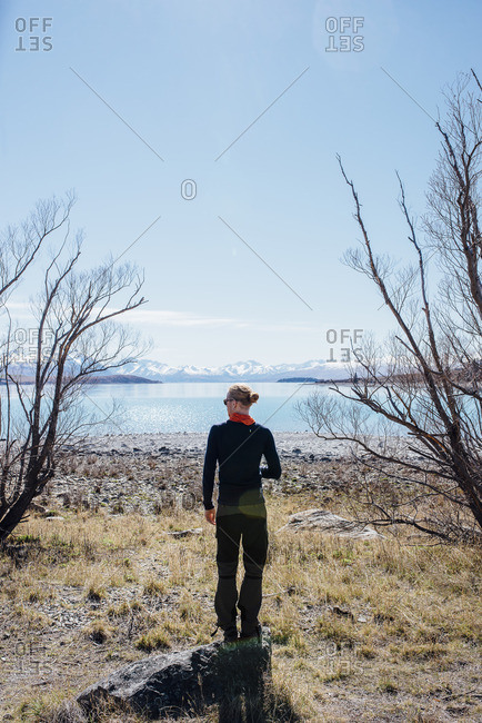 Man standing on a rock looking out over a lake and distant mountains