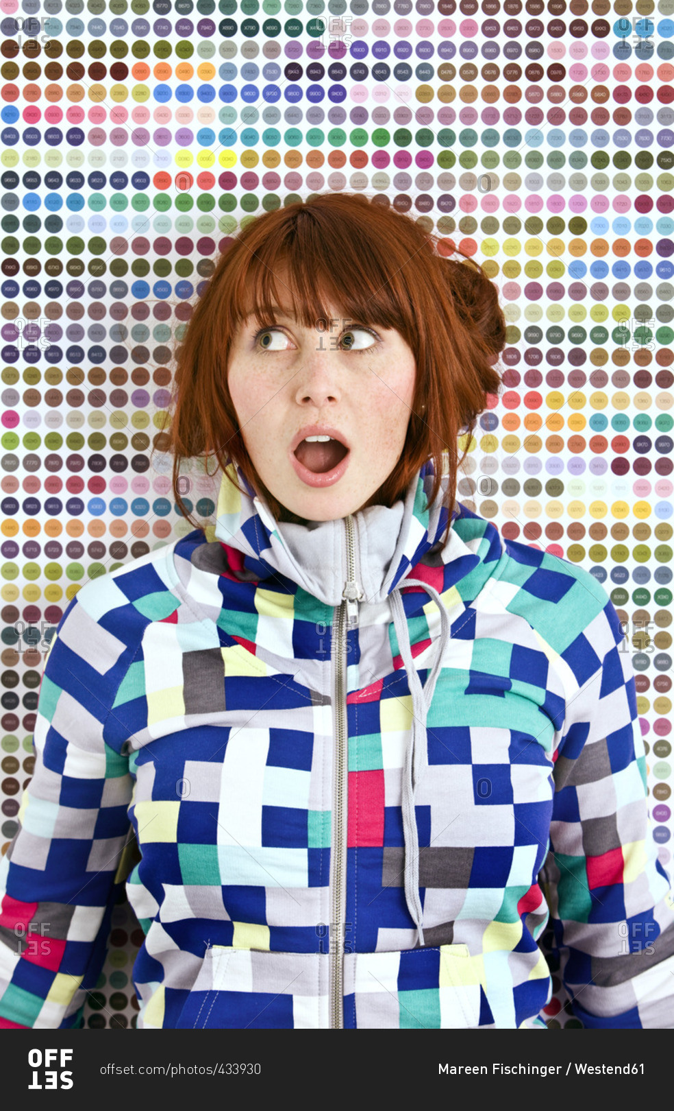 Young woman wearing patterned jacket in front of dotted wall