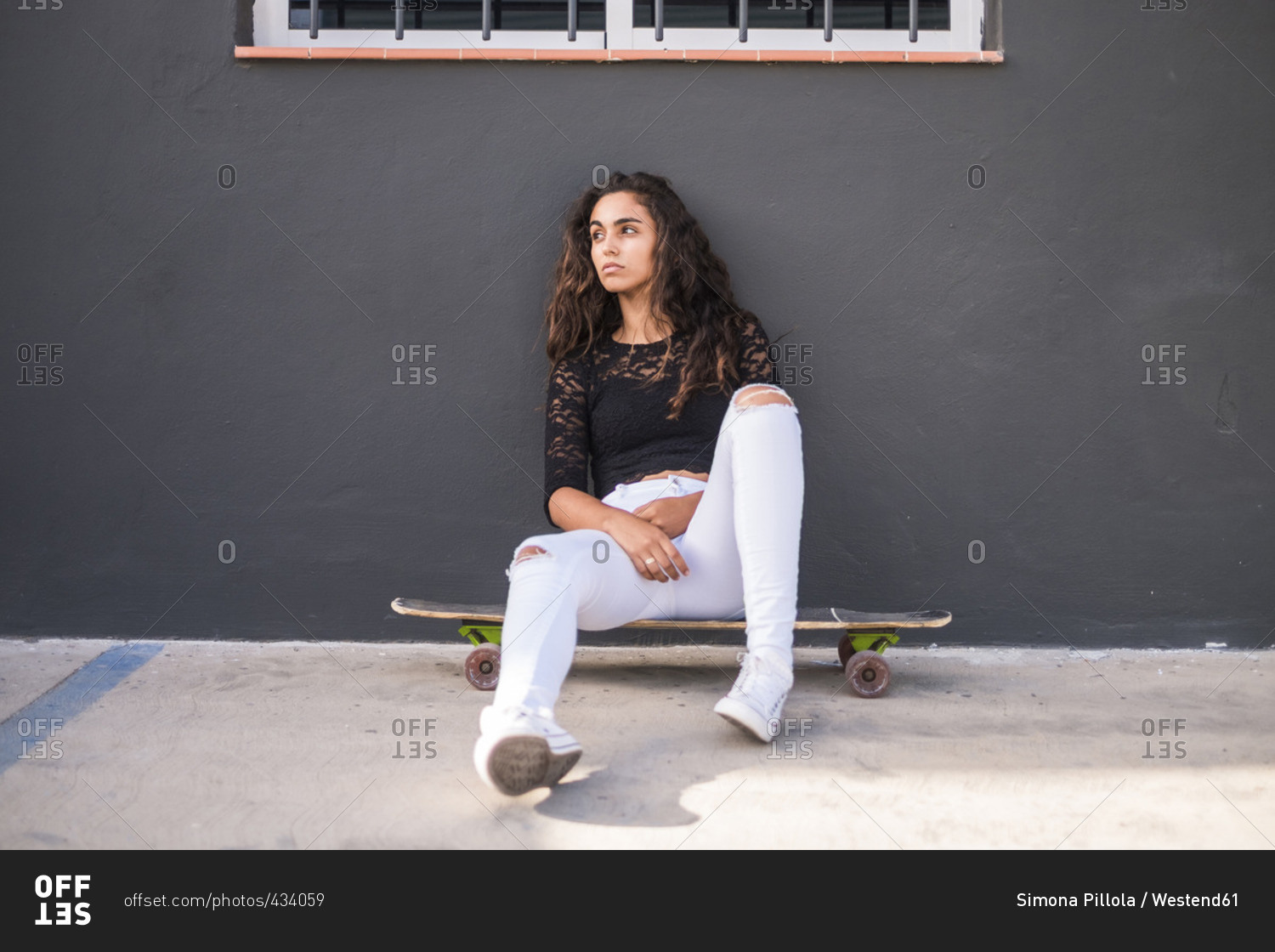 Teenage girl sitting on skateboard