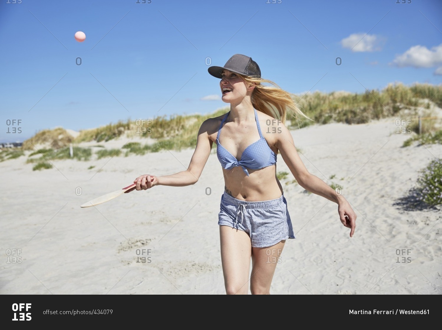 Happy young woman on the beach playing beach paddles