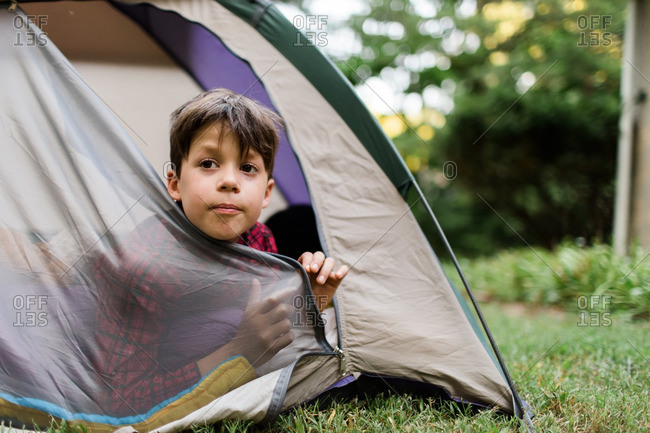 Boy poking his head from an open tent door