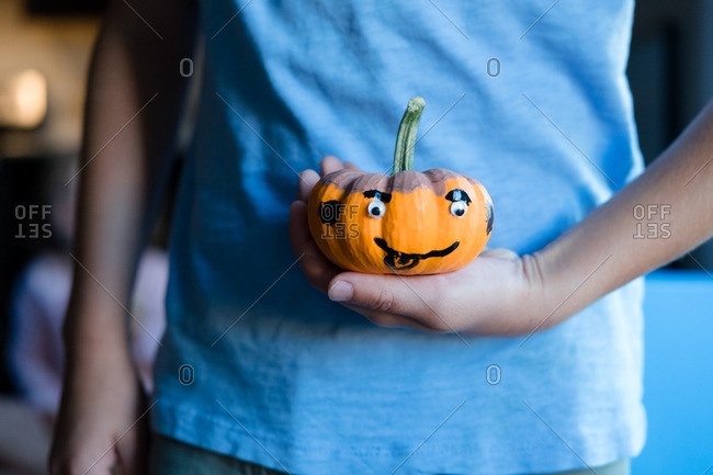 Child holding a decorated mini pumpkin