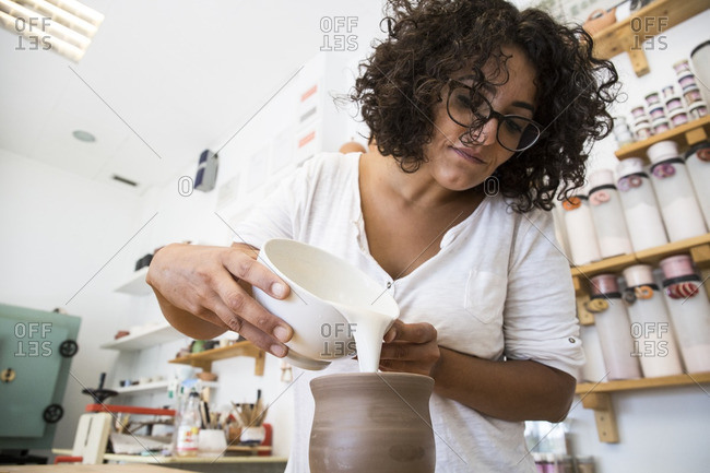 Woman enameling a ceramic mug