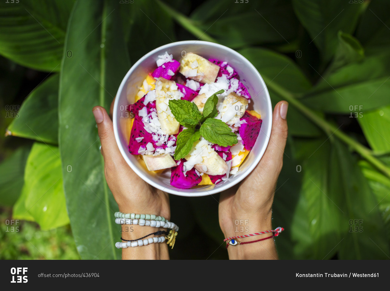 Woman's hands holding bowl of tropical fruit salad