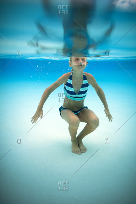 Young girl swimming underwater in a pool.