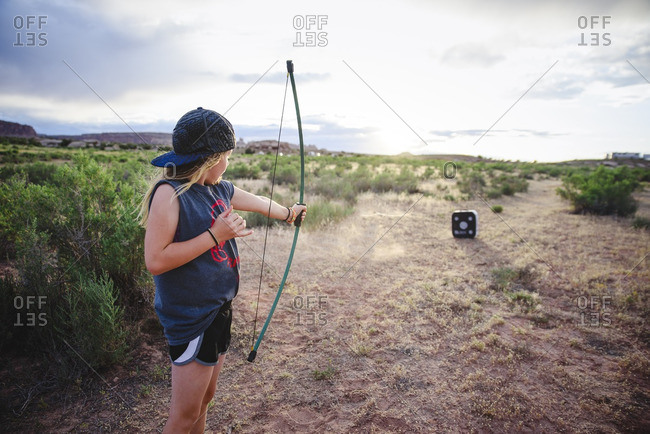 Girl practicing archery in rural setting