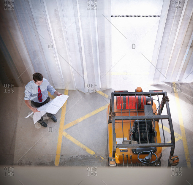 Man holding plans next to fork lift in joinery