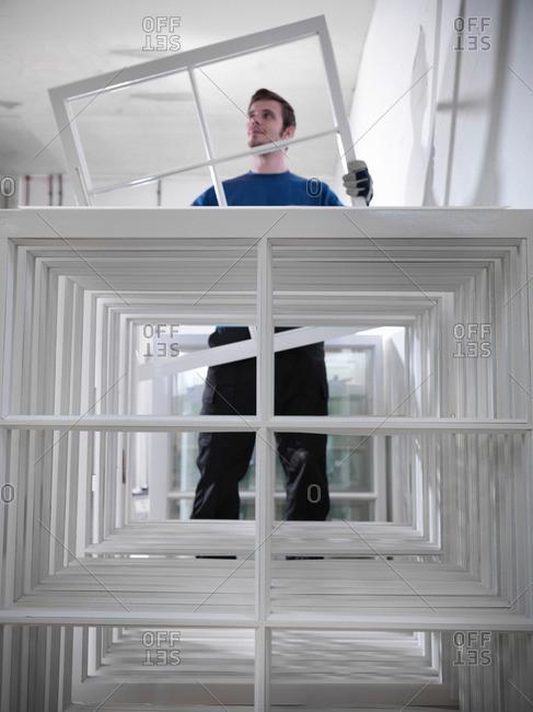 Worker holding window frames in joinery