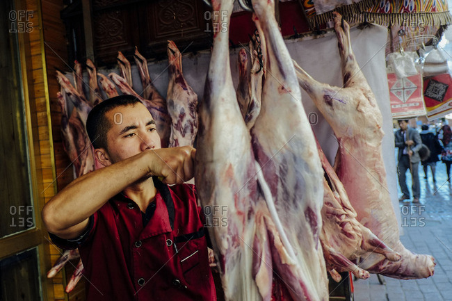 Kashgar, China - May 7, 2016: Uighur man piercing meat for lamb skewers in old Kashgar