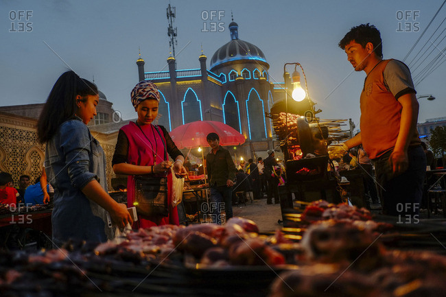 Kashgar, China - May 5, 2016: Uighur women buying street food at the night market in old Kashgar
