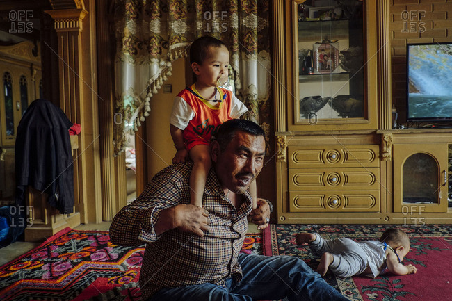 Kashgar, China - May 4, 2016: Uighur man playing with his grandchildren at his apartment