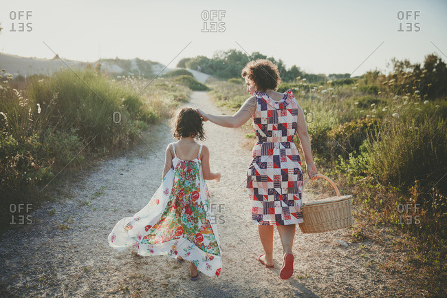 Mother and daughter holding hands walking to the beach