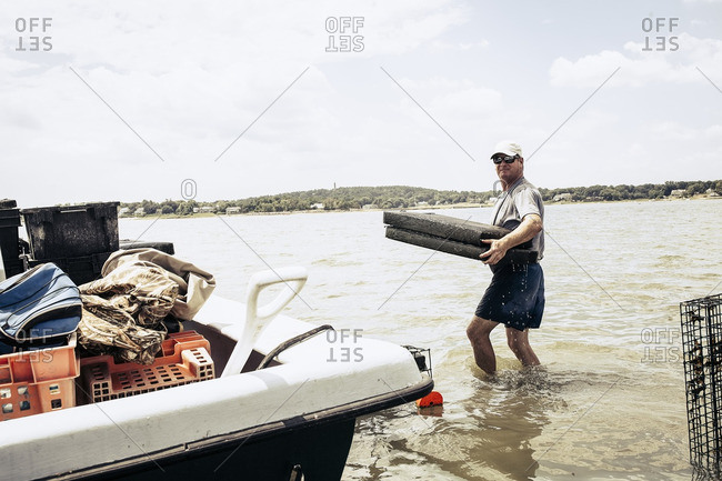 Man carrying oyster cages in sea