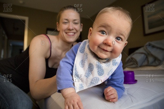 Mom holding smiling baby on bed